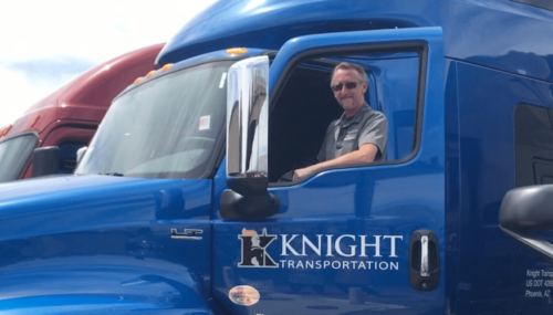 Driver standing in the door of his truck showing Knight Transportation logo